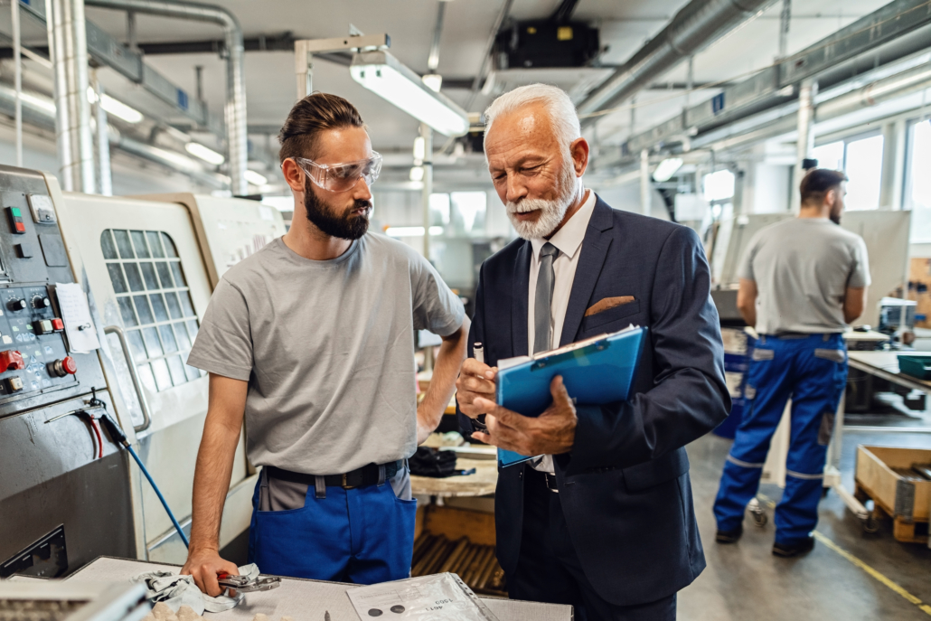 Senior businessman and manual worker reading reports in a factory. Our Process